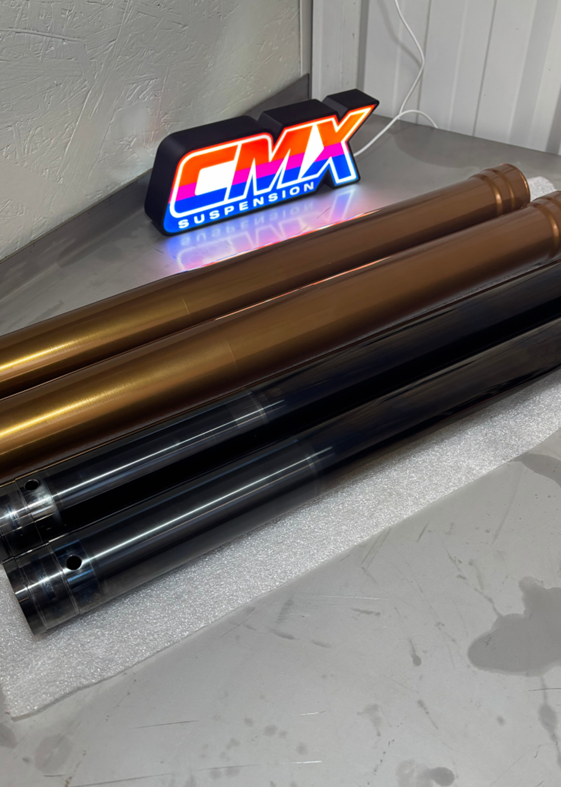 Tubes de fourche traités posés devant le logo lumineux CMX Suspension